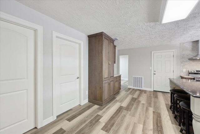 42252 State Highway 87, Orange, TX 77632 - kitchen featuring stainless steel electric stove, light wood-type flooring, baseboards, wall chimney range hood, and a textured ceiling