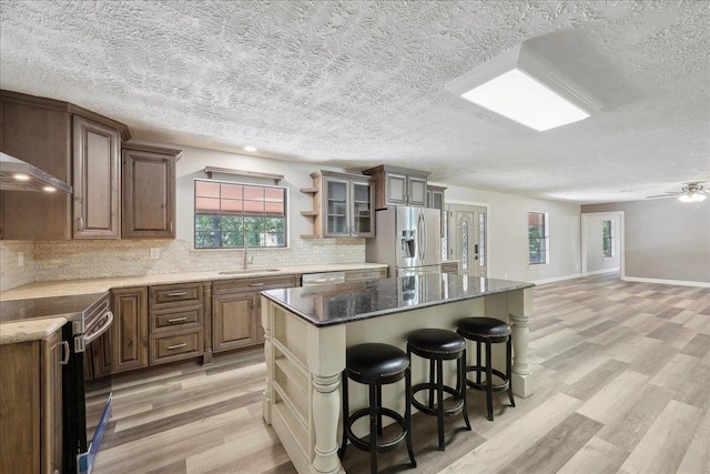 42252 State Highway 87, Orange, TX 77632 - kitchen with appliances with stainless steel finishes, a sink, a textured ceiling, backsplash, and light wood-style floors