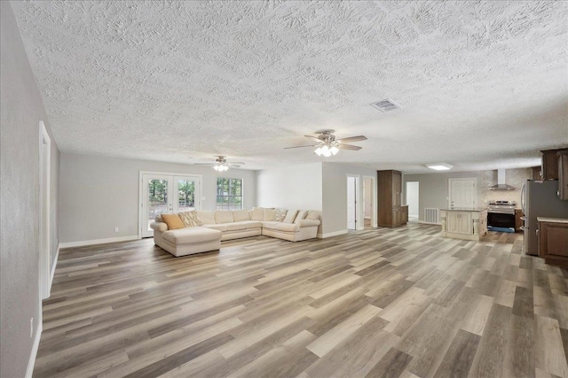 42252 State Highway 87, Orange, TX 77632 - living room with light wood finished floors, baseboards, a textured ceiling, and a ceiling fan