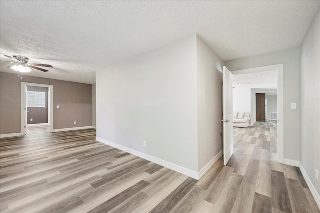 42252 State Highway 87, Orange, TX 77632 - spare room featuring light wood-style flooring, a textured ceiling, ceiling fan, and baseboards