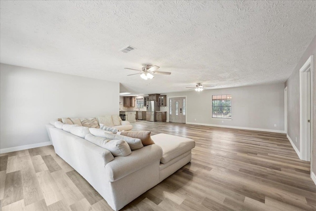 42252 State Highway 87, Orange, TX 77632 - living room featuring ceiling fan, light wood-type flooring, a textured ceiling, and baseboards