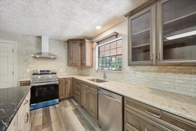 42252 State Highway 87, Orange, TX 77632 - kitchen with stainless steel appliances, wall chimney range hood, a sink, light wood finished floors, and backsplash