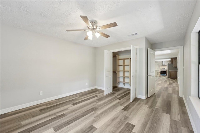 42252 State Highway 87, Orange, TX 77632 - unfurnished bedroom featuring light wood-style flooring, a textured ceiling, baseboards, and a ceiling fan