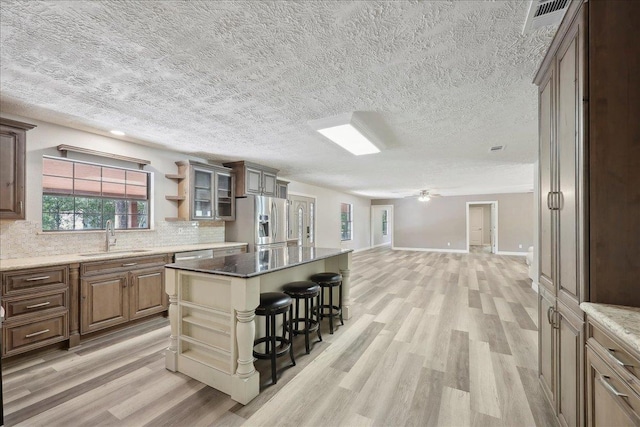 42252 State Highway 87, Orange, TX 77632 - kitchen featuring a sink, appliances with stainless steel finishes, open shelves, a breakfast bar, and light wood finished floors