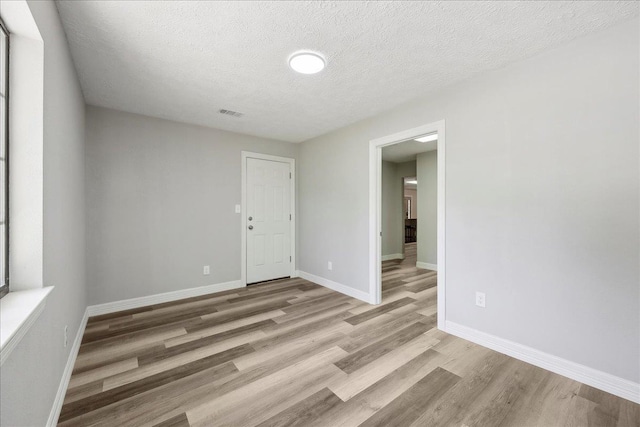 42252 State Highway 87, Orange, TX 77632 - spare room with light wood-type flooring, baseboards, and a textured ceiling