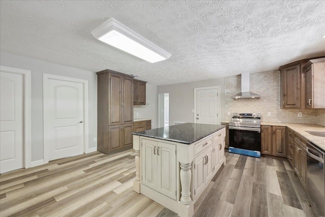 42252 State Highway 87, Orange, TX 77632 - kitchen with stainless steel appliances, wall chimney exhaust hood, light wood-type flooring, dark stone counters, and a center island