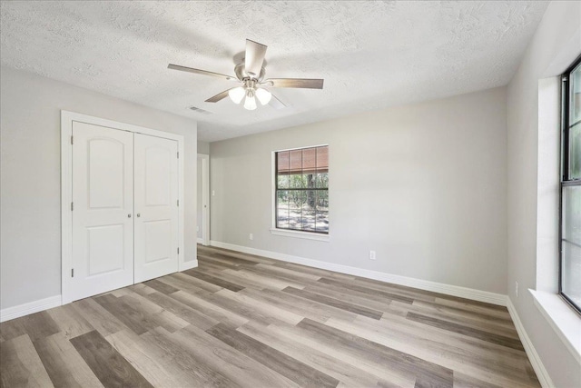 42252 State Highway 87, Orange, TX 77632 - unfurnished bedroom featuring wood finished floors, a textured ceiling, a closet, a ceiling fan, and baseboards