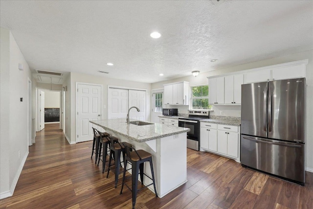 664 W Tram Rd, Vidor, TX 77662 - kitchen with appliances with stainless steel finishes, a sink, a kitchen island with sink, a breakfast bar area, and dark wood finished floors