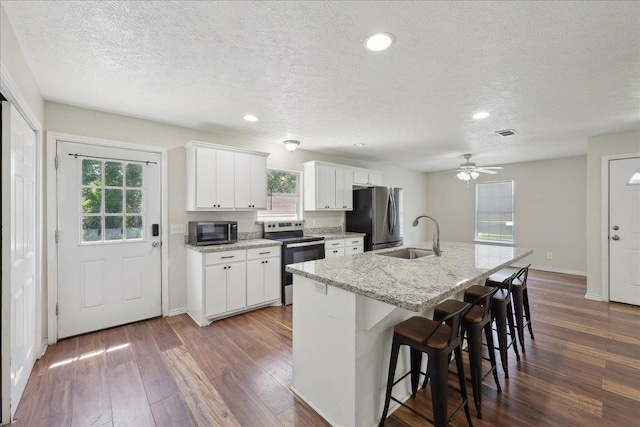664 W Tram Rd, Vidor, TX 77662 - kitchen with stainless steel appliances, a sink, dark wood-style floors, a kitchen island with sink, and a breakfast bar area
