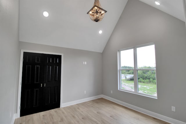 interior space featuring vaulted ceiling, light hardwood / wood-style flooring, an inviting chandelier, and a closet