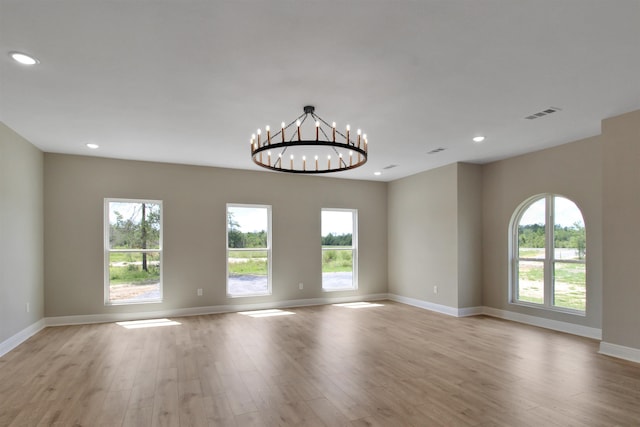 spare room with light hardwood / wood-style flooring and an inviting chandelier