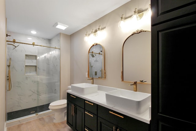 bathroom featuring vanity, toilet, wood-type flooring, and a shower with door