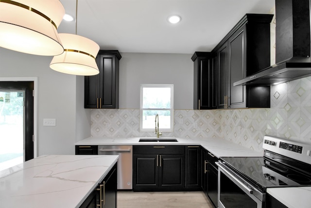 kitchen with sink, wall chimney exhaust hood, decorative backsplash, decorative light fixtures, and stainless steel appliances