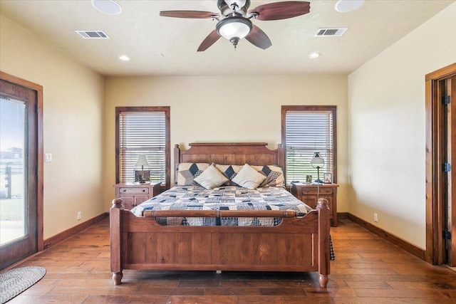 bedroom featuring ceiling fan, dark hardwood / wood-style floors, and multiple windows