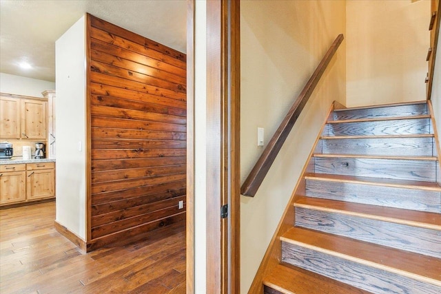 staircase featuring wood-type flooring and wood walls