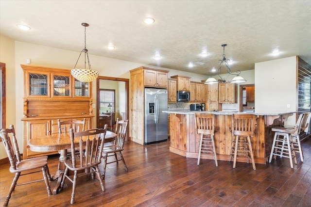 kitchen with hanging light fixtures, appliances with stainless steel finishes, dark hardwood / wood-style flooring, and kitchen peninsula