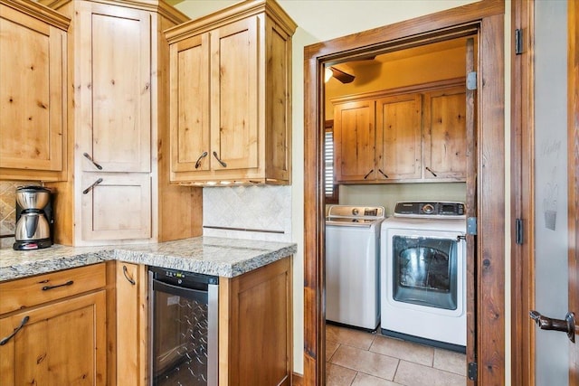 kitchen with light tile patterned floors, washing machine and dryer, light stone counters, decorative backsplash, and beverage cooler