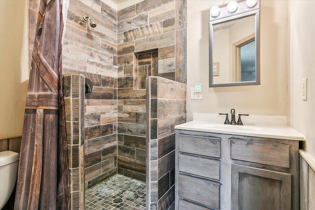 bathroom featuring vanity, toilet, and tiled shower