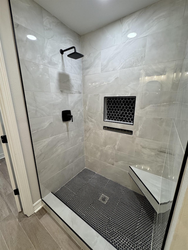 full bath featuring a tile shower and wood finished floors