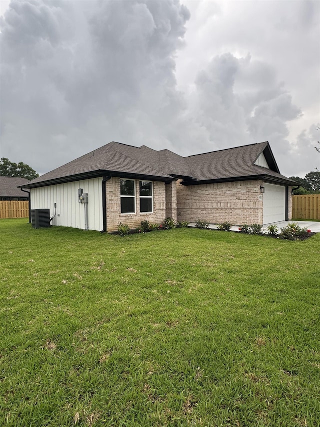 ranch-style home featuring central AC unit, a garage, fence, a front lawn, and a shingled roof