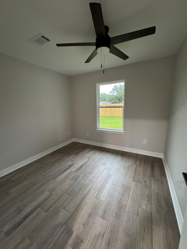 spare room featuring visible vents, dark wood finished floors, ceiling fan, and baseboards