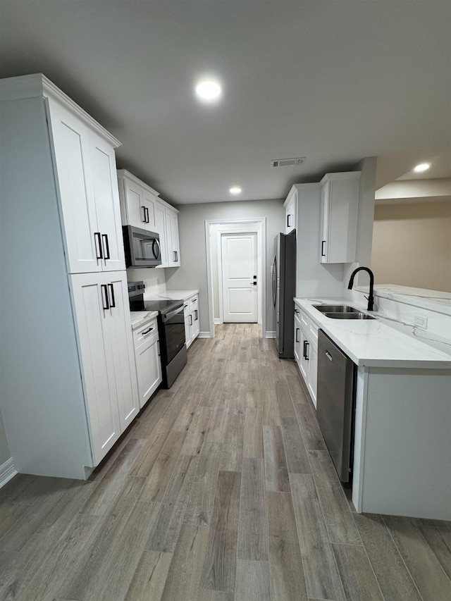 kitchen with visible vents, a sink, light wood-style floors, stainless steel appliances, and white cabinetry