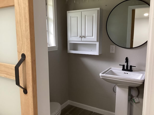 half bathroom featuring baseboards and toilet