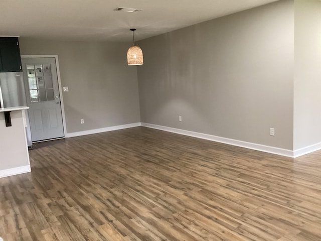 empty room featuring baseboards, visible vents, and dark wood finished floors