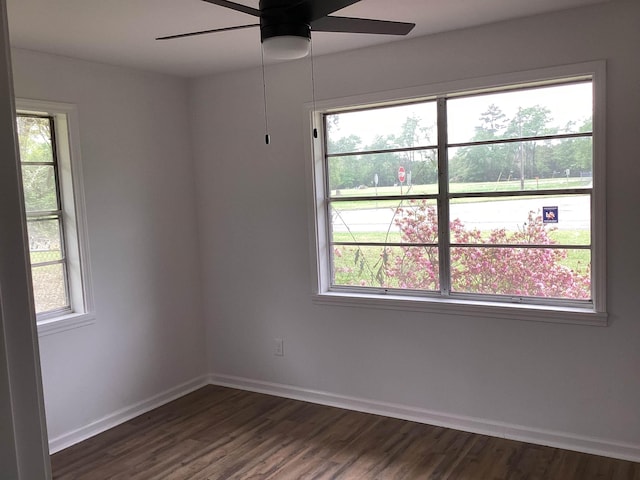spare room featuring a ceiling fan, a healthy amount of sunlight, and dark wood finished floors