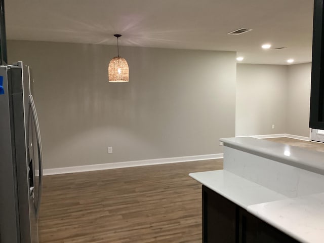 kitchen with light countertops, stainless steel fridge, dark wood-style flooring, baseboards, and pendant lighting