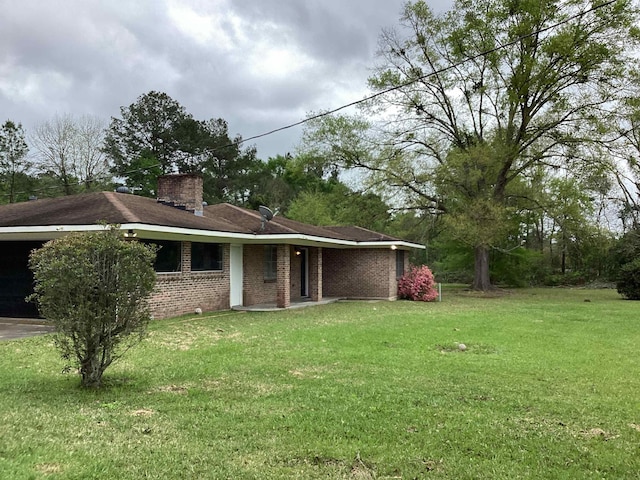 back of house featuring a lawn, a chimney, and brick siding