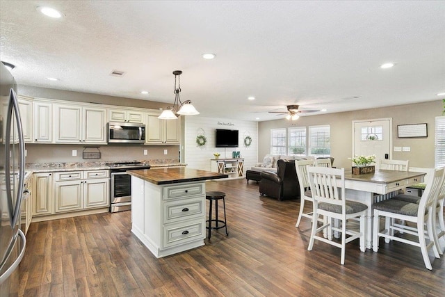 kitchen featuring dark wood-style flooring, wood counters, open floor plan, ceiling fan, and stainless steel appliances