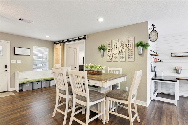 dining space with a textured ceiling, wood finished floors, baseboards, and visible vents