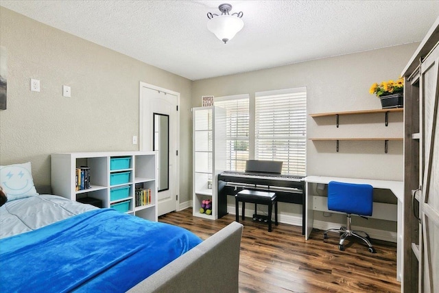 bedroom featuring built in desk, baseboards, a textured ceiling, and dark wood-style floors