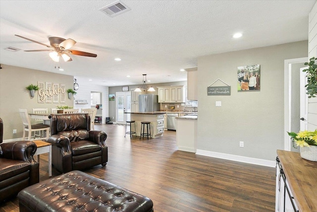 living area with ceiling fan, dark wood-type flooring, a textured ceiling, visible vents, and baseboards