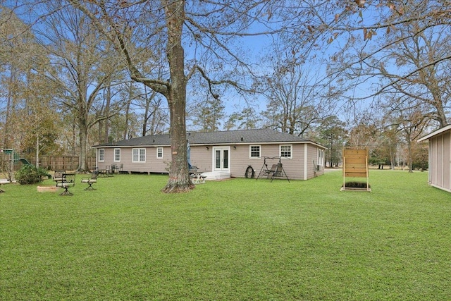 rear view of property featuring entry steps, french doors, fence, and a yard