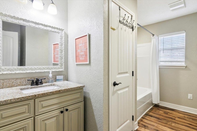 bathroom with vanity, baseboards, a textured wall, shower / tub combo with curtain, and wood finished floors