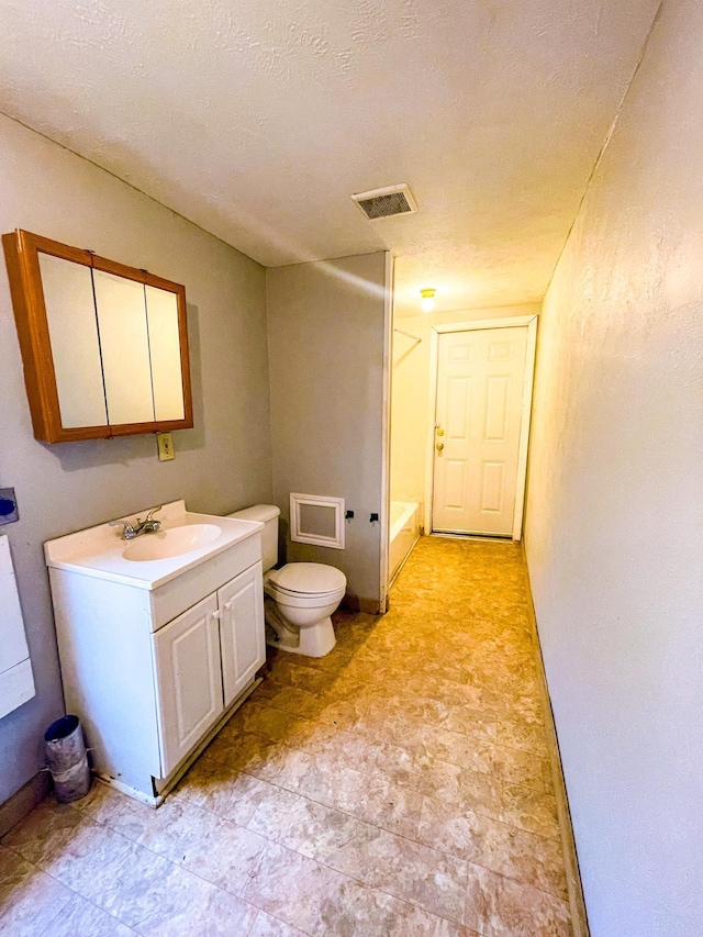 bathroom with vanity, toilet, and a textured ceiling