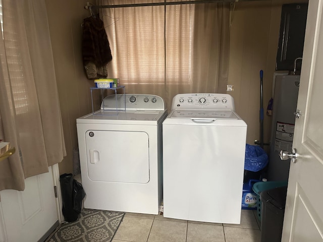 laundry area featuring electric water heater, light tile patterned floors, and independent washer and dryer