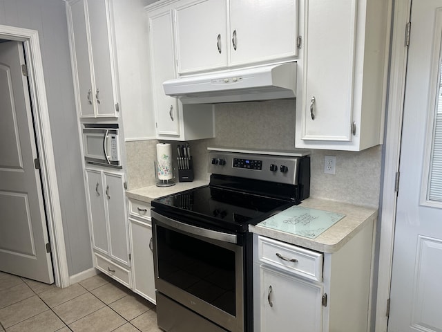 kitchen with tasteful backsplash, light tile patterned floors, white cabinets, and stainless steel range with electric stovetop