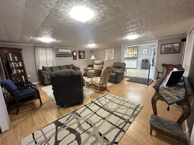 living room with a wall mounted air conditioner, ornamental molding, and light wood-type flooring