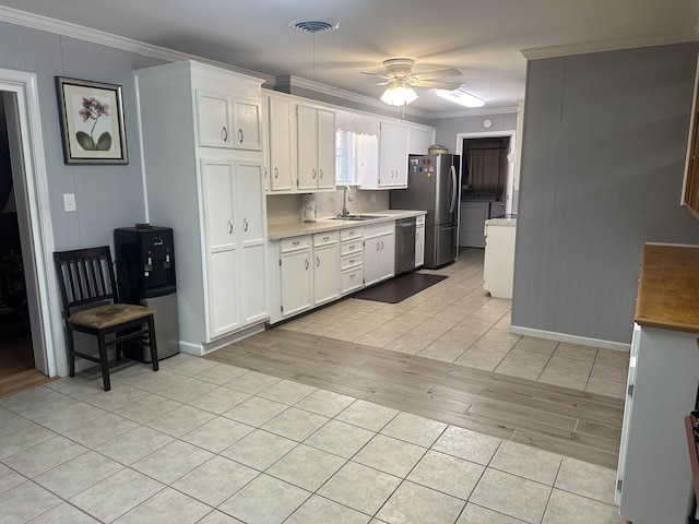 kitchen featuring sink, white cabinetry, stainless steel appliances, ornamental molding, and washing machine and clothes dryer