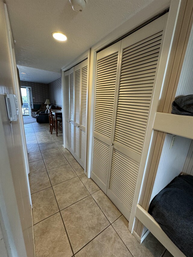 hall featuring light tile patterned floors and a textured ceiling