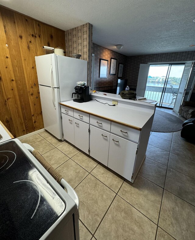 kitchen featuring white cabinets, stove, a textured ceiling, and wooden walls