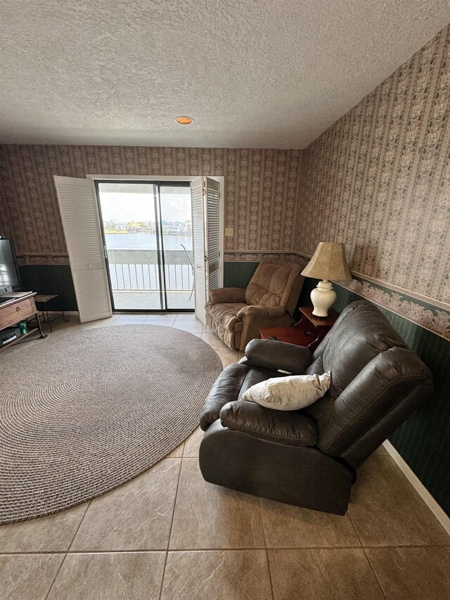 living room featuring a water view, light tile patterned flooring, and a textured ceiling