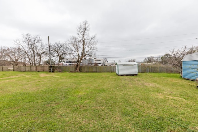 view of yard with a fenced backyard, an outdoor structure, and a storage shed