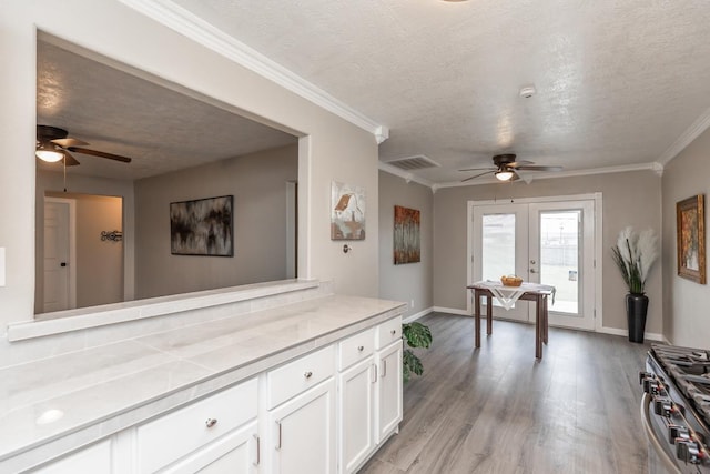 interior space with white cabinets, light countertops, ornamental molding, french doors, and light wood-type flooring