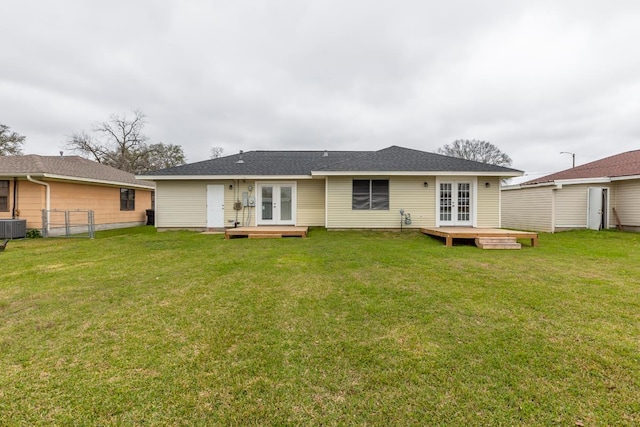 back of property featuring a deck, french doors, a lawn, and a shingled roof