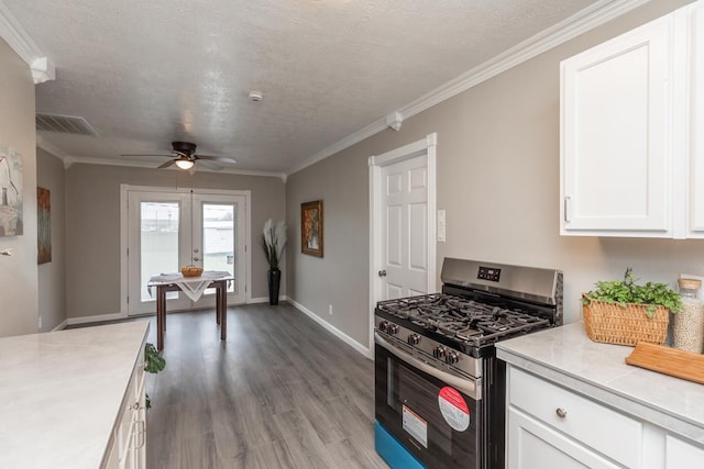 kitchen with stainless steel gas range oven, white cabinetry, light countertops, ornamental molding, and french doors