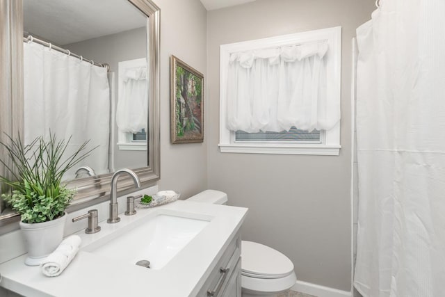 bathroom with baseboards, vanity, and toilet